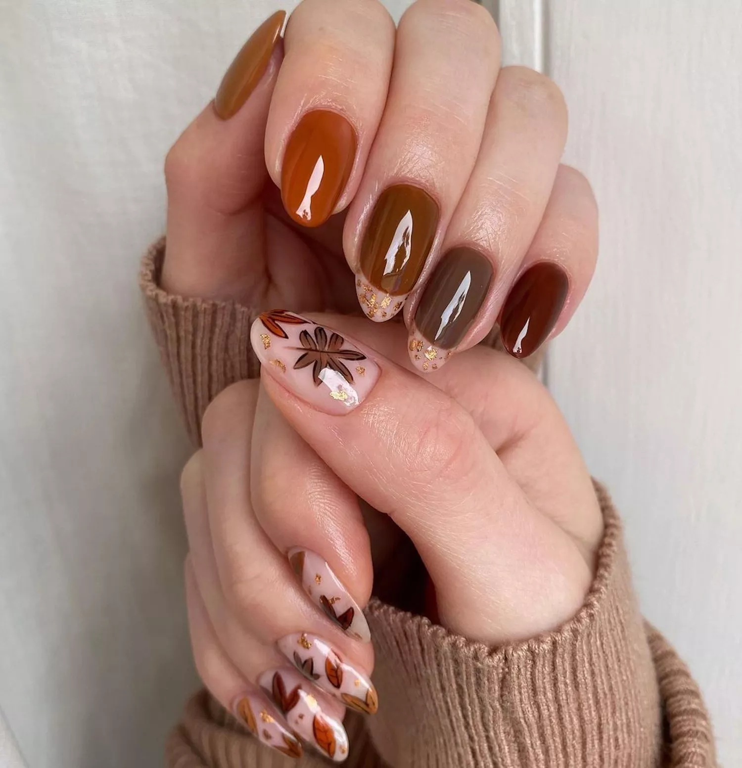 Close up of a manicure in shades of brown with fall accents