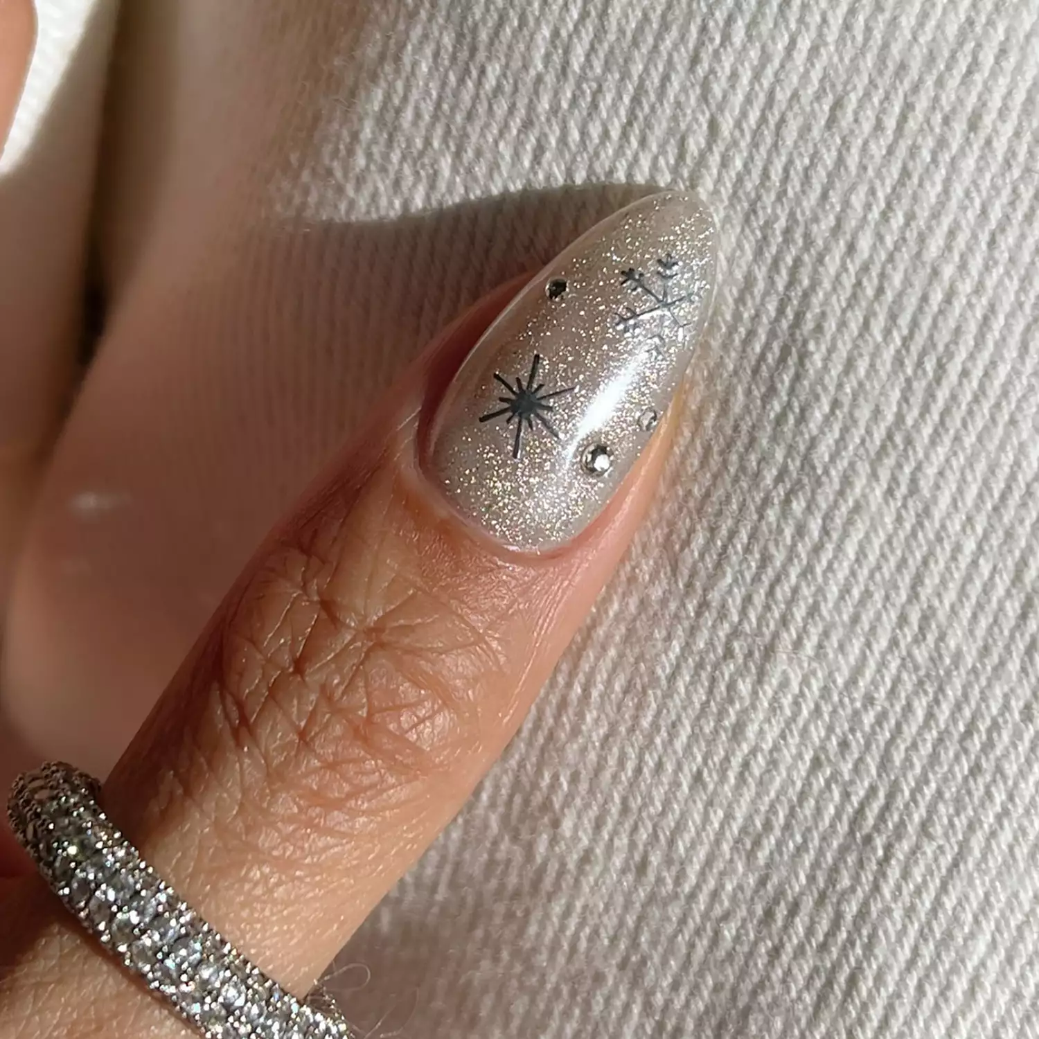 55+ Winter Nail Design Ideas 2025 24 A shimmery thumb nail with snowflake and star details