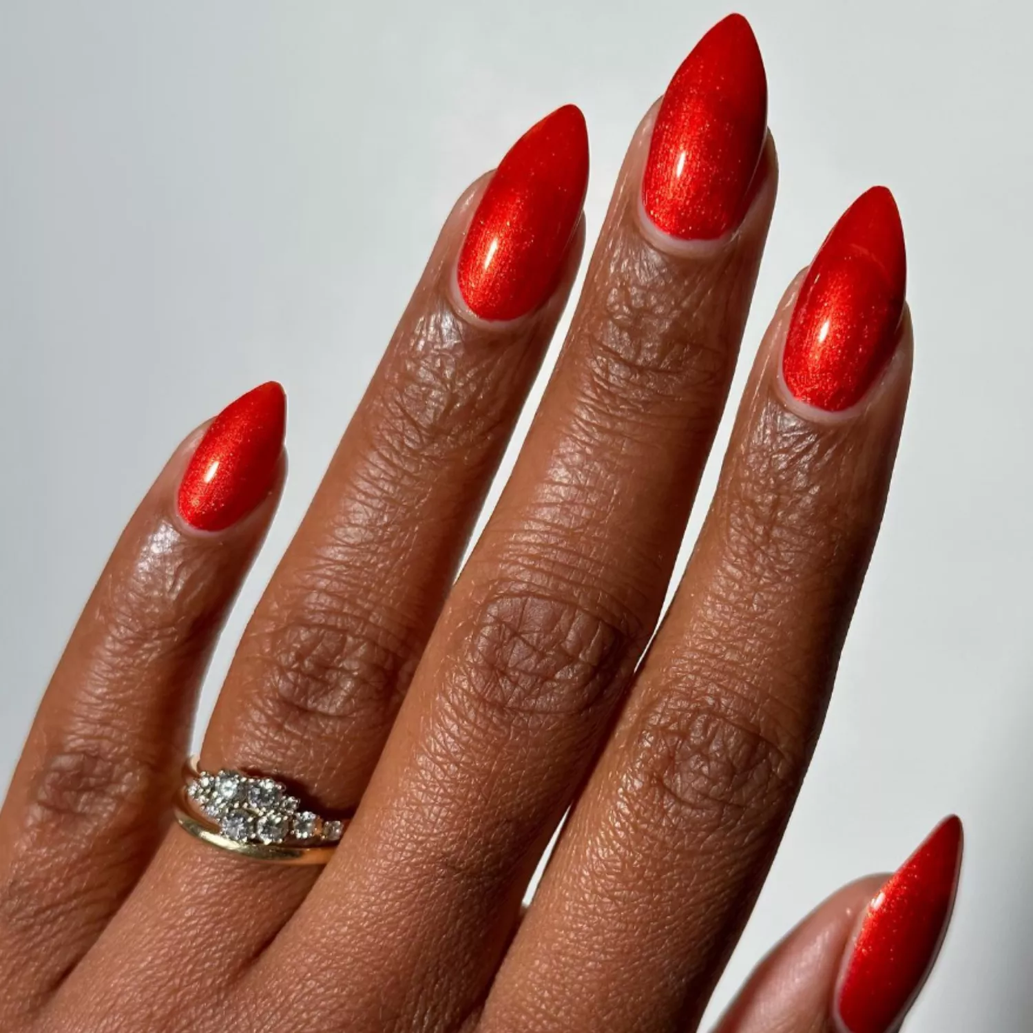 close up of hand with fresh manicure, sparkly apple red nails