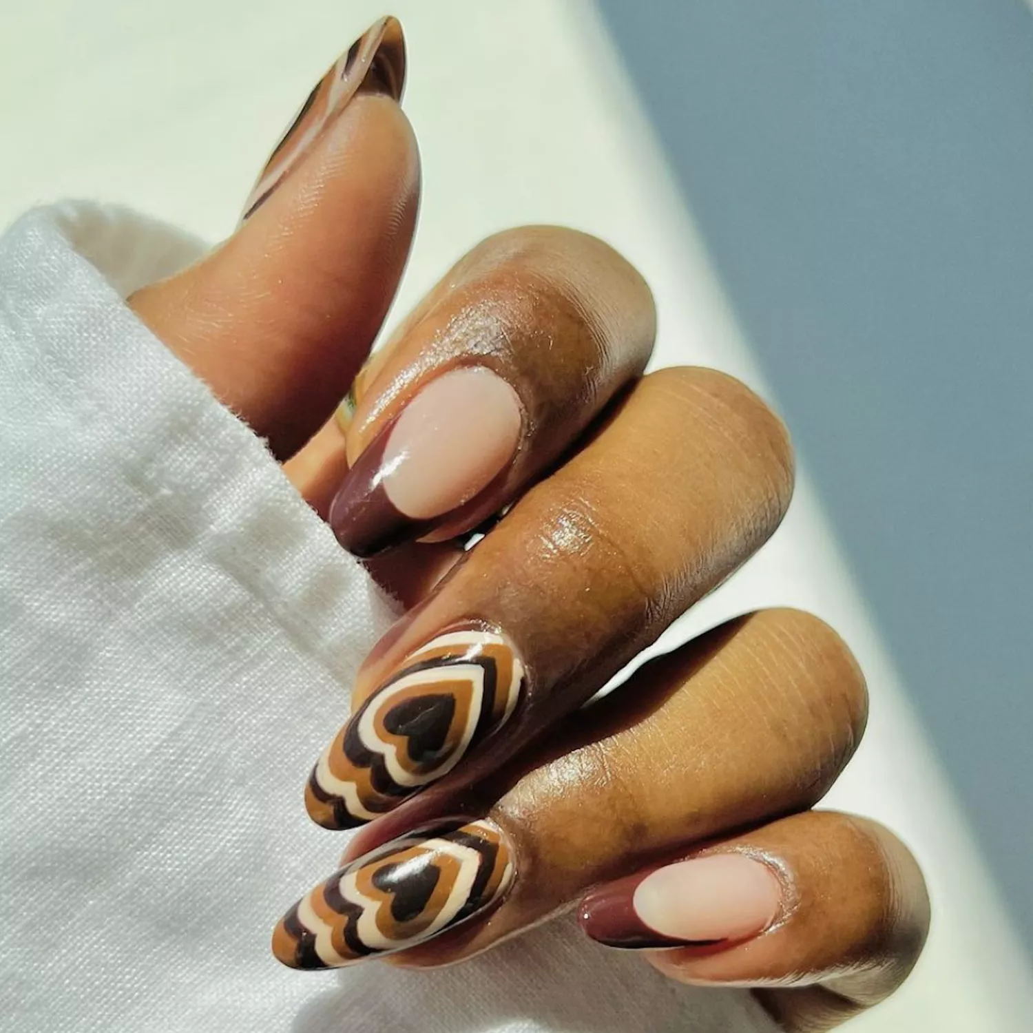 Almond-shaped nails with heart-shaped brown latte art nail design