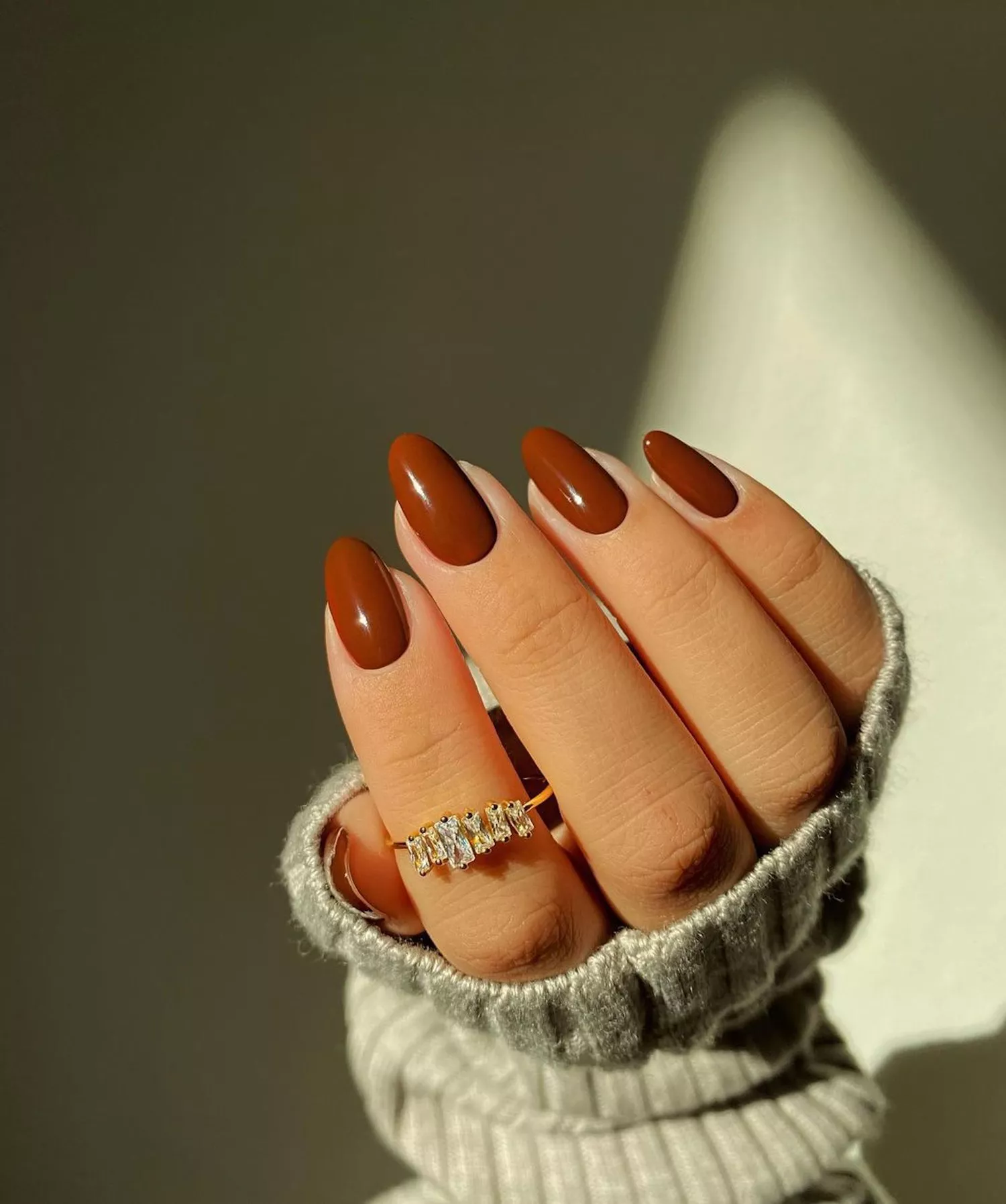 Close up of an almond-shaped manicure with glossy chocolate nail polish