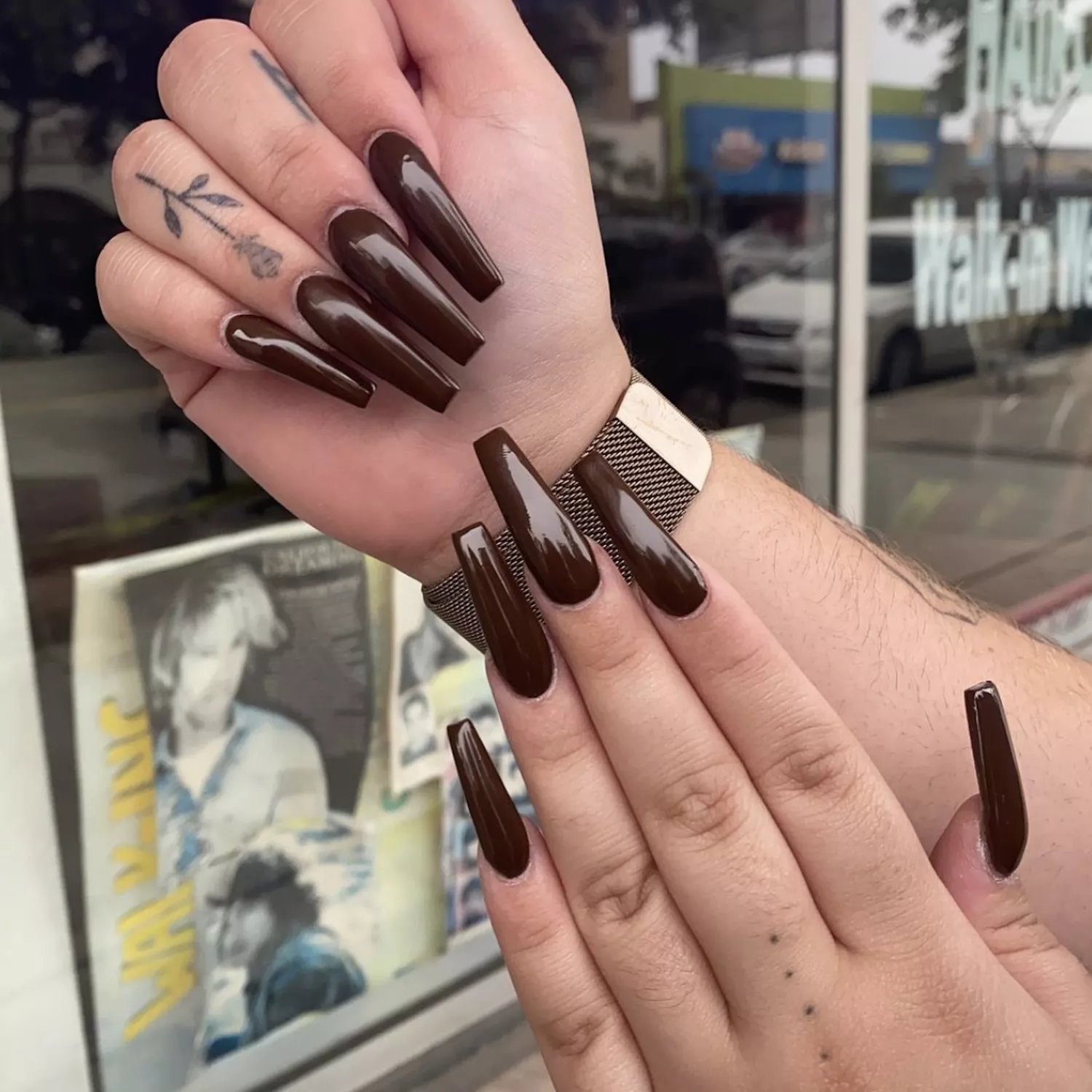 Long, coffin-shaped nails with dark brown polish